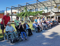 Große Gruppe Senior*innen im Rollstuhl mit Betreuung vor dem Haus Maria