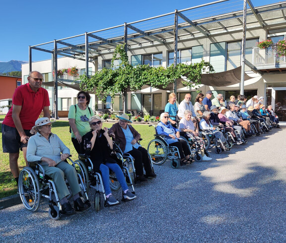 Große Gruppe Senior*innen im Rollstuhl mit Betreuung vor dem Haus Maria