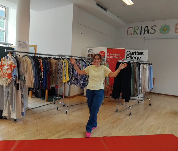 Person präsentiert auf rotem Teppich Kleidung aus dem Angebot von „Mode auf Rädern“ im St. Hemma Haus.