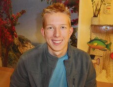 ein junger blonder Mann lächelt freundlich in die Kamera