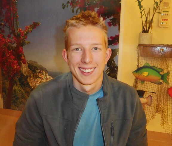 ein junger blonder Mann lächelt freundlich in die Kamera