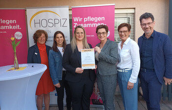 Stolz präsentieren Mitarbeiter*innen und Ehrengäste das Zertifikat "HPCPH" für das Pflegewohnhaus "Haus Theresia" in Feldkirchen.