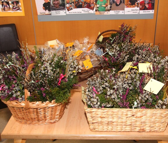 Mehrere Körbe gefüllt mit liebevoll gebundenen Palmbuschen stehen bereit. Die farbenfrohen Sträuße aus Weidenkätzchen, Grünzweigen und bunten Bändern sind sorgfältig arrangiert und warten darauf, im Pflegewohnhaus gesegnet zu werden