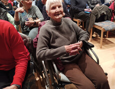 Bewohner*in des Pflegewohnhauses sitzt im Rollstuhl im Zuschauerbereich.