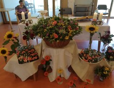 Blumen, Kerzen und Altartisch im Raum dekoriert mit Kräutersträußen und Sonnenblumen
