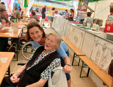 Bewohner*in und Begleitperson sitzen gemeinsam im Festzelt des Bleiburger Wiesenmarkts.
