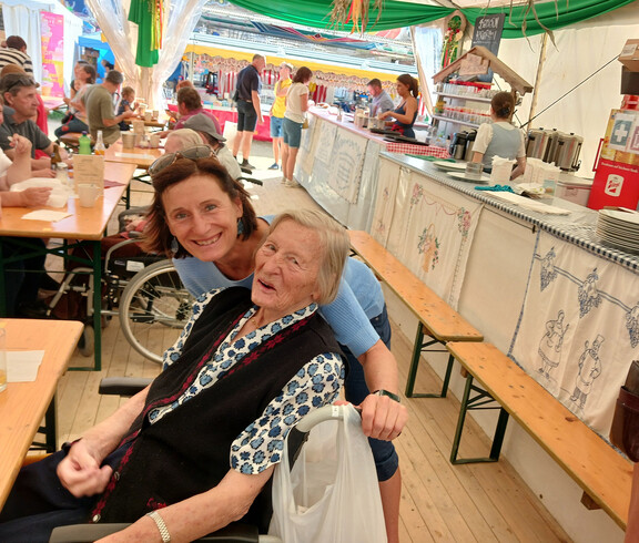 Bewohner*in und Begleitperson sitzen gemeinsam im Festzelt des Bleiburger Wiesenmarkts.