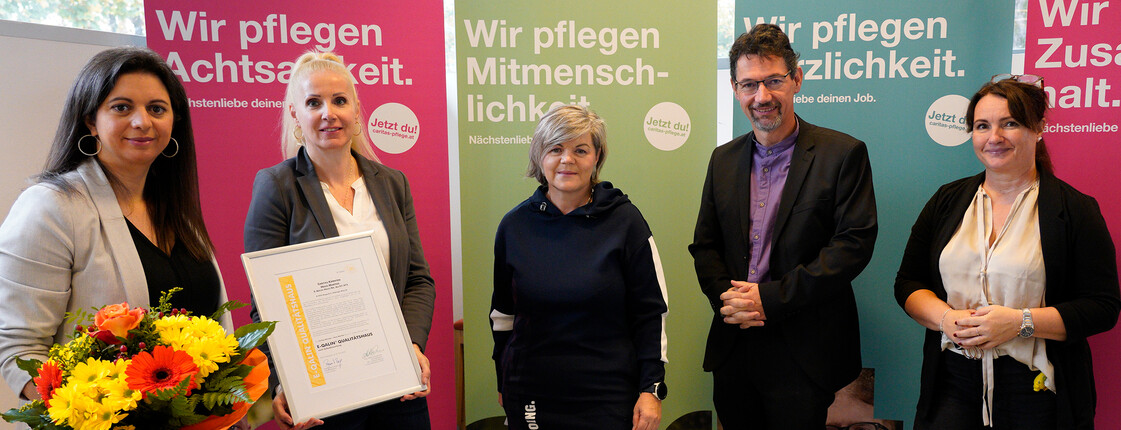 Mitarbeiter*innen des Pflegewohnhaus "Haus Martha" präsentieren gemeinsam mit Caritasdirektor Ernst Sandriesser und Bereichsleiterin Donata Rössler-Merlin das Zertifikat E-Qalin.