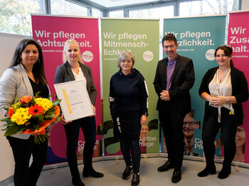 Mitarbeiter*innen des Pflegewohnhaus "Haus Martha" präsentieren gemeinsam mit Caritasdirektor Ernst Sandriesser und Bereichsleiterin Donata Rössler-Merlin das Zertifikat E-Qalin.