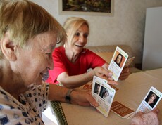 Caritas Mitarbeiterin der Hauskrankenpflege spielt mit Klientin Karten