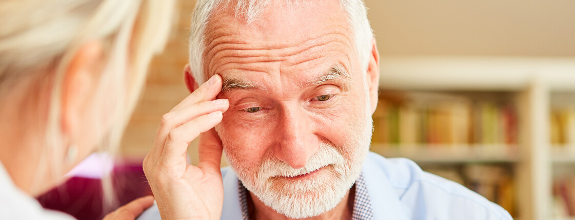 Alter Mann greift sich mit der Hand an die Schläfe