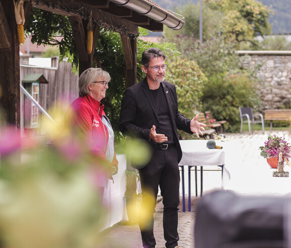 Zwei Personen sprechen bei der Eröffnung des Herbstfestes im Garten des Caritas St. Hemma-Hauses.