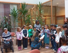 Kinder lesen anlässlich des Vorlesetages im Pflegewohnhaus den anwesenden Bewohnerinnen und Bewohnern in gemeinsamer Runde aus vorbereiteten Texten vor.