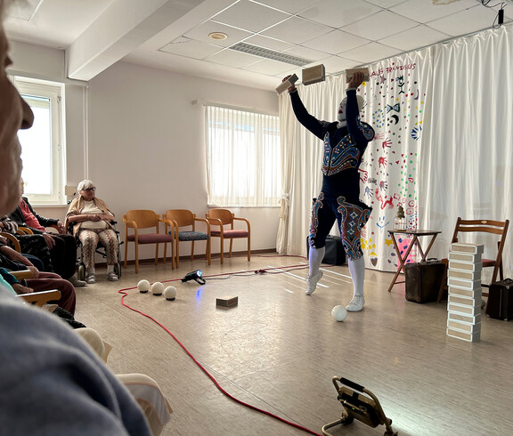 Artist wirft Holzklötze in die Luft und tritt vor Bewohner*innen in Haus Franziskus auf.