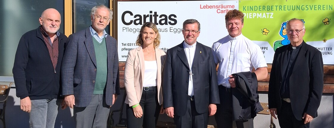 Gruppenfoto vor dem Eingang des Caritas Pflegewohnhauses Eggersdorf: Sechs Personen stehen vor einer Tafel mit dem Schriftzug „Caritas Pflegewohnhaus Eggersdorf“ und dem Logo des Kinderbetreuungsvereins Piepmatz.