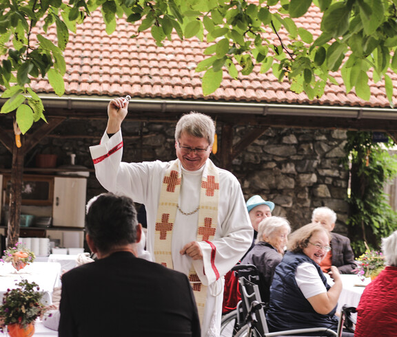 Geistlicher segnet die Gäste während der Messe beim Herbstfest im Garten des Caritas St. Hemma-Hauses.