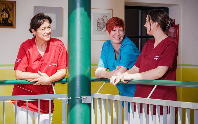 Drei Pflegekräfte im Innenbereich im Gespräch über das Arbeiten in der Caritas Pflege