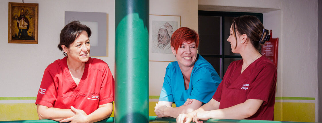 Drei Pflegekräfte im Innenbereich im Gespräch über das Arbeiten in der Caritas Pflege