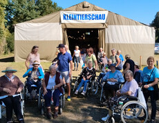 Gruppe Senior*innen mit Begleitpersonen vor Zelt mit Aufschrift „Kleintierschau“