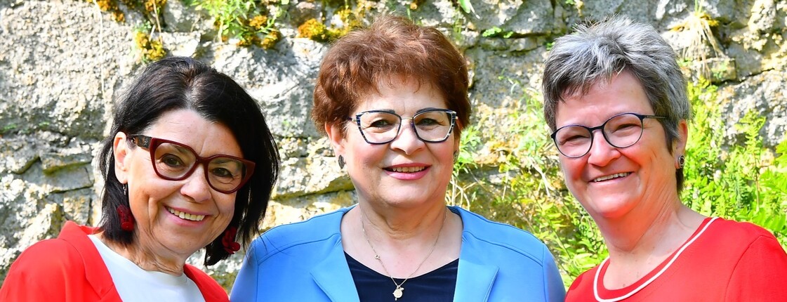 Drei ältere Frauen mit Brille schauen frontal in die Kamera