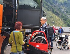 Rollstuhlnutzer*in wird mithilfe einer Hebebühne in Reisebus gehoben