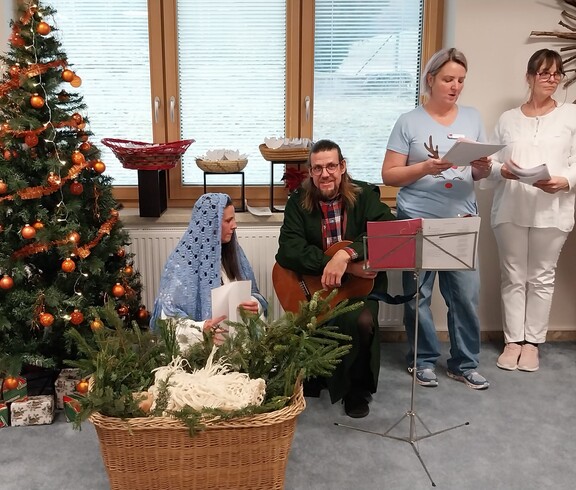 Mitarbeitende und Zivildienstleistende gestalten Krippenspiel neben geschmücktem Weihnachtsbaum