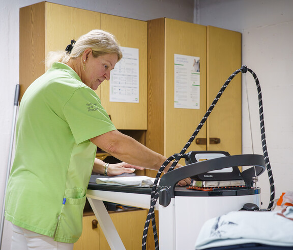 Pflegekraft bügelt Kleidung in der Wäscherei des Hauses Magdalena.
