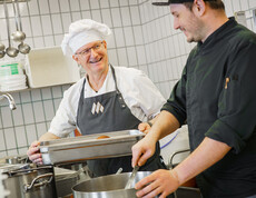 Zwei Küchenmitarbeiter kochen in der hauseigenen Großküche.