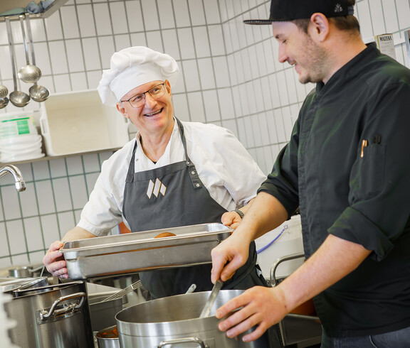 Zwei Küchenmitarbeiter kochen in der hauseigenen Großküche.
