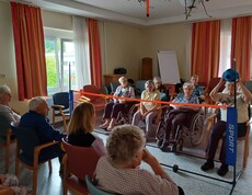 Einige Bewohner*innen des Caritas Pflegewohnhauses Lannach sitzen auf Stühlen oder in Rollstühlen und spielen gemeinsam über ein niedriges Netz mit einem Softball. Die Szene zeigt Freude, Bewegung und gemeinsames Erleben.