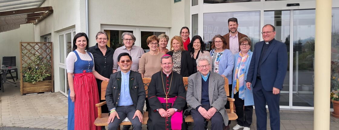 Gruppenfoto vor dem Eingang des Pflegewohnhauses mit Teilnehmenden eines Besuchs, die gemeinsam im Außenbereich versammelt sind.