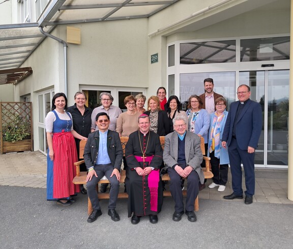 Gruppenfoto vor dem Eingang des Pflegewohnhauses mit Teilnehmenden eines Besuchs, die gemeinsam im Außenbereich versammelt sind.