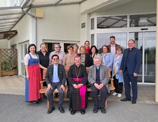 Gruppenfoto vor dem Eingang des Pflegewohnhauses mit Teilnehmenden eines Besuchs, die gemeinsam im Außenbereich versammelt sind.