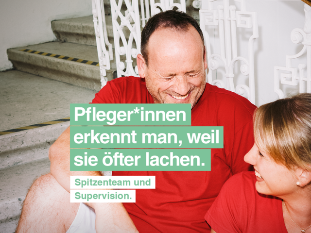 Ein Mann und eine Frau mit roten T-Shirts mit Caritas-Logo sitzen auf den Stiegen und lachen gemeinsam. Die Frau hat einen Aktenordner in der Hand. Text im Bild: Pfleger*innen erkennt man, weil sie öfter lachen. Spitzenteam und Supervision."