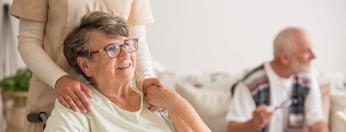 Eine Seniorin im Rollstuhl wird von einer Pflegekraft getröstet.