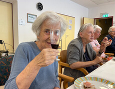 Bewohner*in hält ein Glas Rotwein während der Weinverkostung im Haus Franziskus.