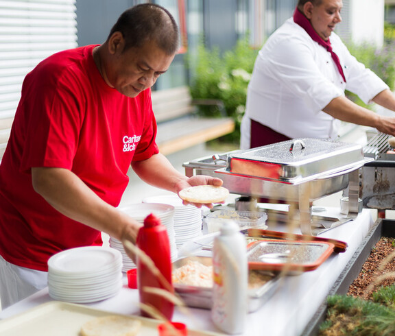Reginaldo Ulaye aus dem Haus St. Teresa serviert leckere Ćevapčići vom Grill.