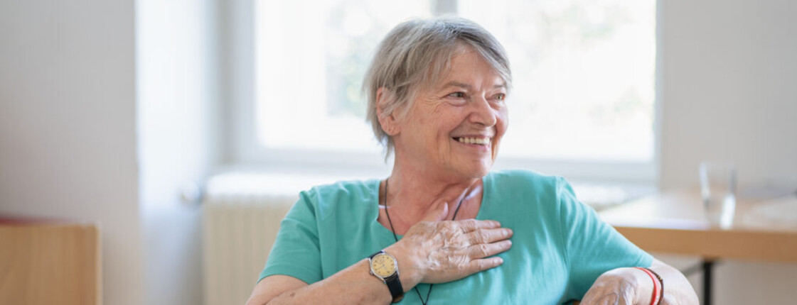 Frau sitzt an Tisch und lächelt