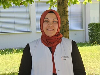 Frau mit rotem Kopftuch und einer weißen Caritas Pflege Weste