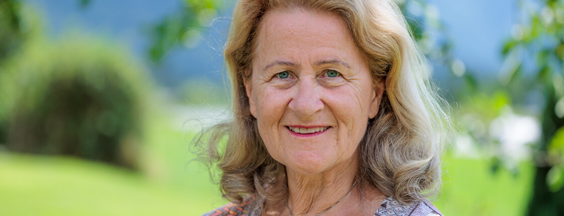 Erholungswochen für pflegende Angehörige Portrait einer lächelden Senorin in einem grünen Garten.
