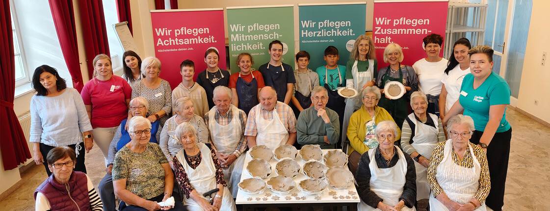Gruppenfoto im Haus Elisabeth in St. Andrä mit Besucher*innen und Bewohner*innen beim kreativen Arbeiten mit Ton.