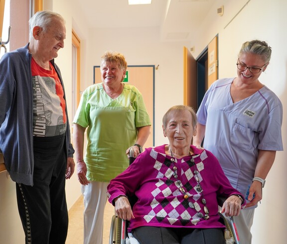 Zwei Bewohner*innen und zwei Pflegerinnen stehen am Gang.