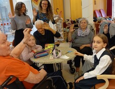 In einem Gemeinschaftsraum des Pflegewohnhauses sitzen Kinder und Bewohnende gemeinsam an einem Tisch beim kreativen Gestalten.