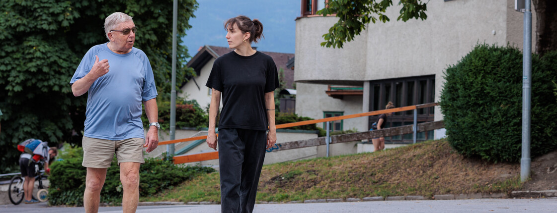 Eine Ehrenamtliche begleitet einen Angehörigen regelmäßig bei Spaziergängen in der Nachbarschaft.