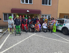 Große Gruppe verkleideter Bewohner*innen und Mitarbeitender vor dem Eingang von Haus Klara während der Faschingsfeier.