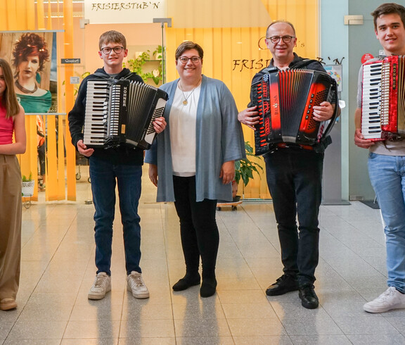 Eine Gruppe von vier Musikern mit Akkordeons und Klarinette, zusammen mit einer weiteren Person in der Mitte. 
