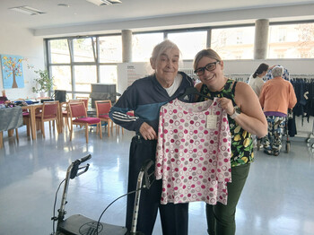 Bewohnerin und Mitarbeiterin halten ein pink gemustertes Oberteil in heller Umgebung