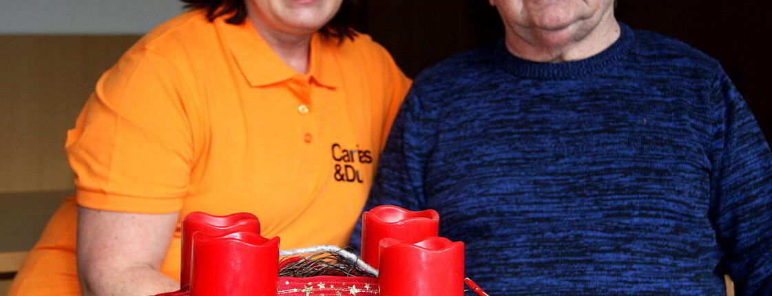 Eine Frau und ein Mann sitzen beim Adventkranz