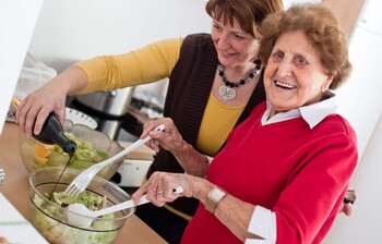 Zwei Frauen richten Salat an und lachen