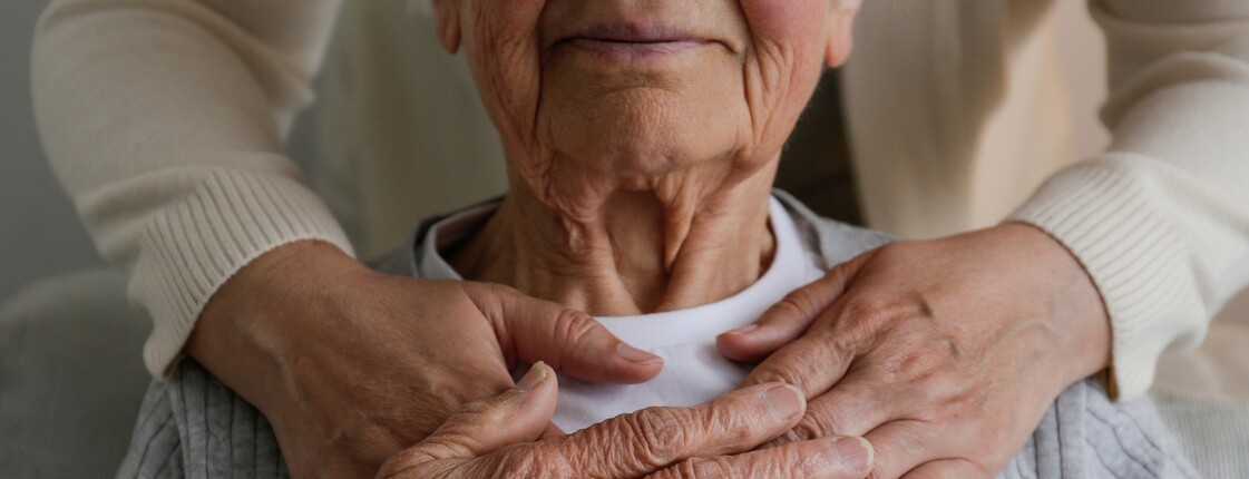 Zwei Hände umarmen eine alte Frau